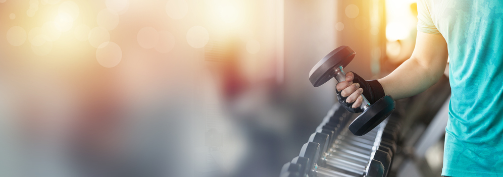 Close up of hand holding metal dumbbell from the rack in the gym. Hand of muscular man picking heavy metal dumbbell in the gym.<br /> double exposure with bokeh, banner cover concept.